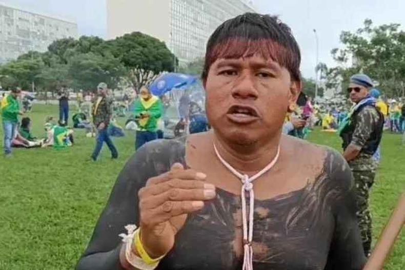 Indgena fala e gesticula; ao fundo manifestantes bolsonaristas no gramado da Esplanada dos Ministrios 