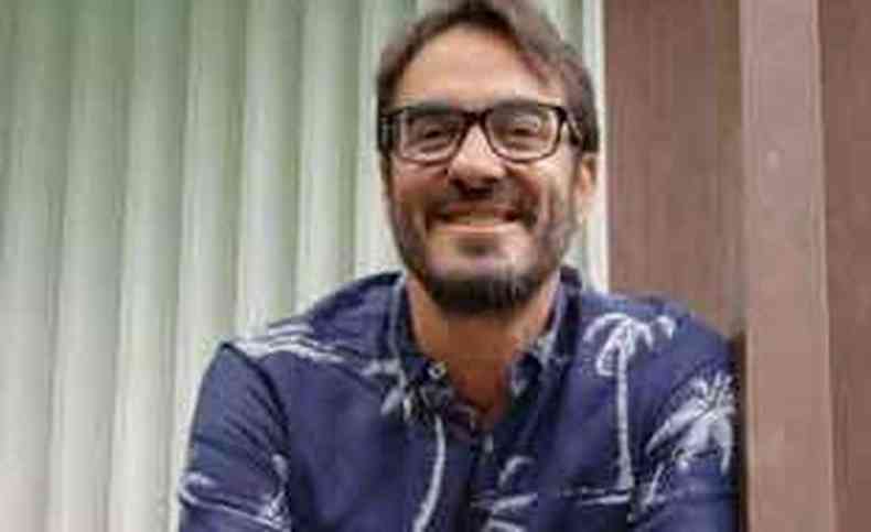 Bernardo Lobo, de camisa estampada e óculos, encostado num parapeito, sorri 