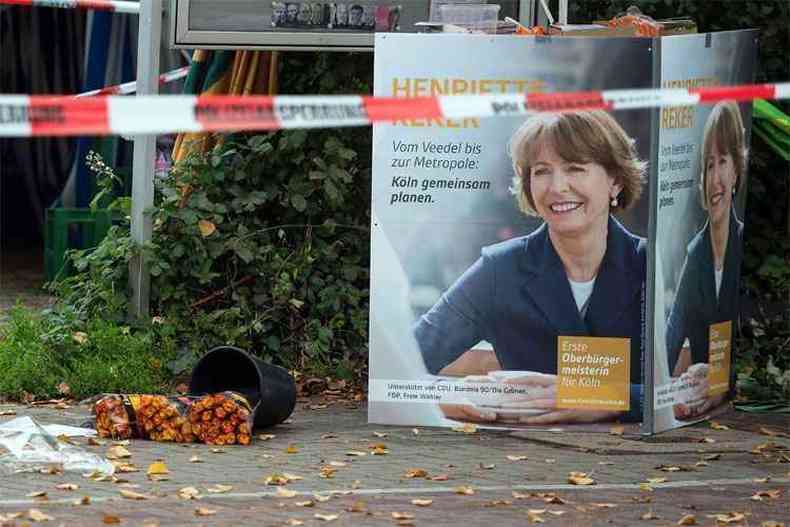 Flores foram deixadas perto de um cartaz de campanha no local onde Henriette Reker foi atacada.(foto: AFP PHOTO / DPA / FEDERICO GAMBARINI GERMANY OUT )