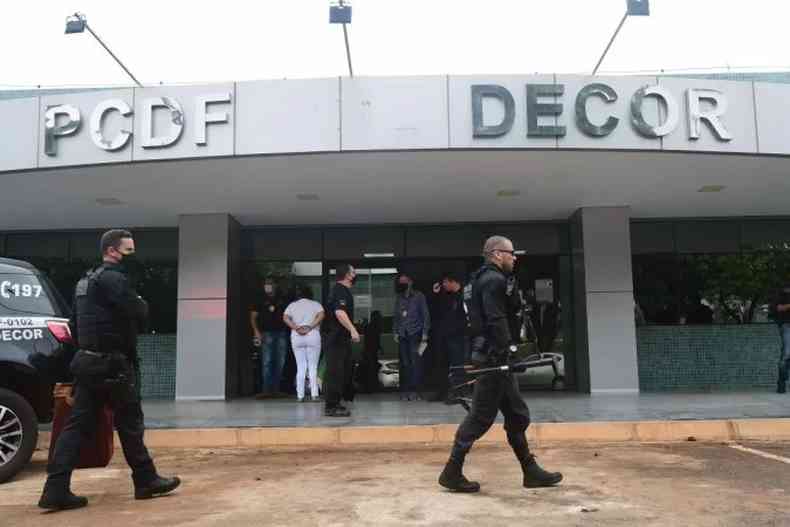 Policiais caminham em frente a delegacia do DF