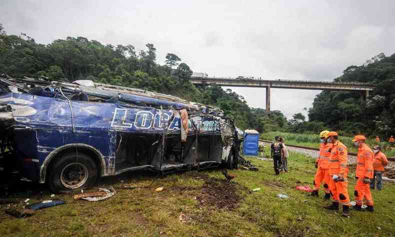 nibus destrudo em rea de gramado. Bombeiros ao lado. Ao fundo aparece a ponte de onde o coletivo caiu. 