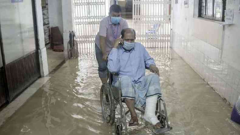 Homem em cadeira de rodas em um corredor inundado