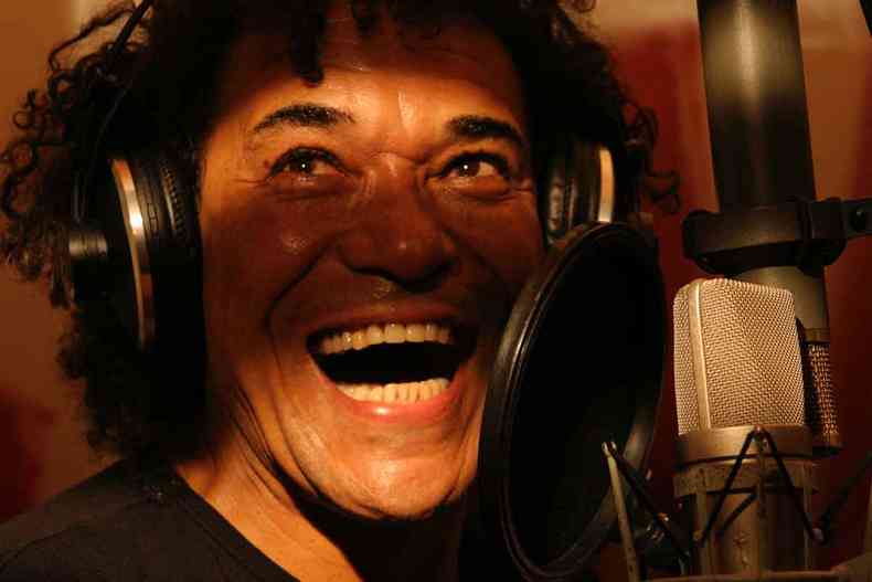 Marku Ribas sorri, cantando em frente ao microfone no estdio 