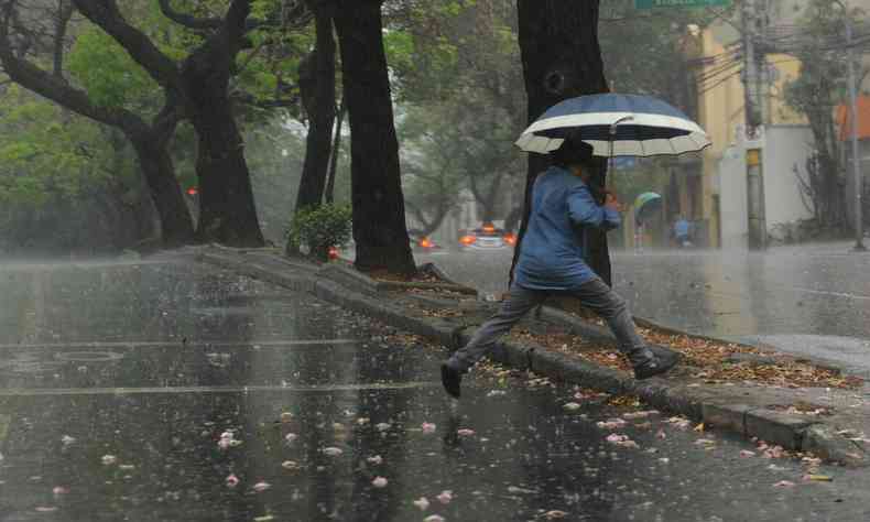 homem de camisa azul correndo da chuva 