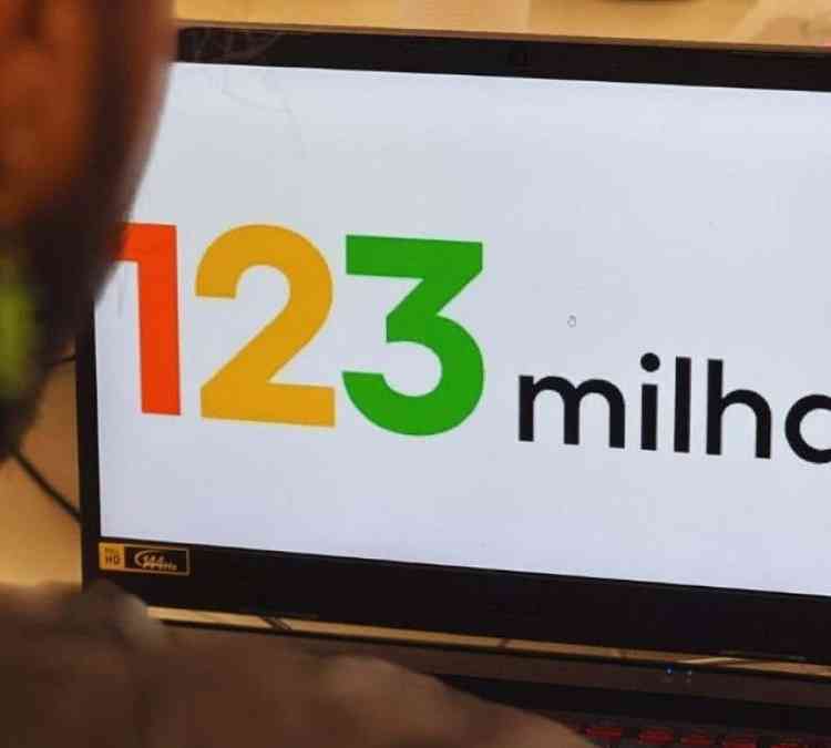 Homem olha tela de computador onde est exibida a logomarca da 123 Milhas