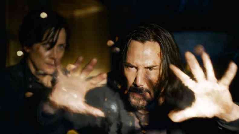 Keanu Reeves interpretando seu personagem Neo ao lado de Trinity de Carrie-Anne Moss ( esquerda)