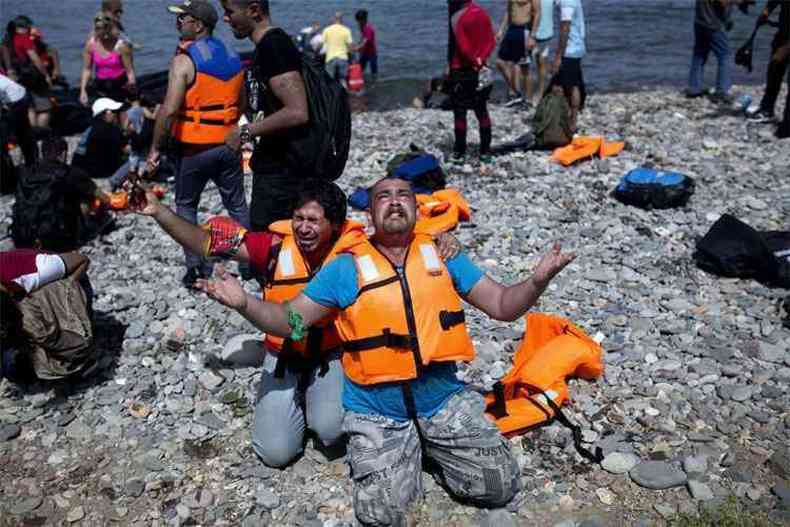 Refugiado da Sria ora para agradecer a chegada  ilha de Lesbos (foto: AFP PHOTO / ANGELOS TZORTZINIS )