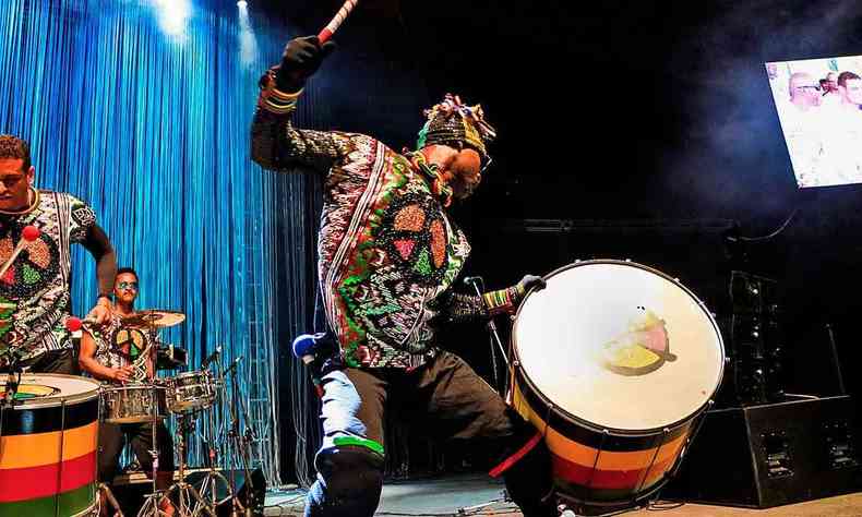 com roupa multicolorida, integrante do Olodum toca tambor no palco