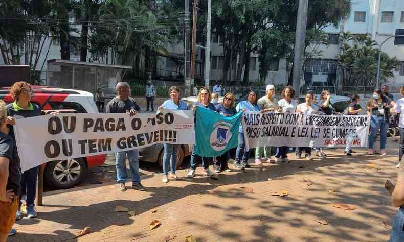 Manifestantes segurando placas. 'Ou paga o piso, ou tem greve' outra diz 'Mais respeito com a enfermagem brasileira'