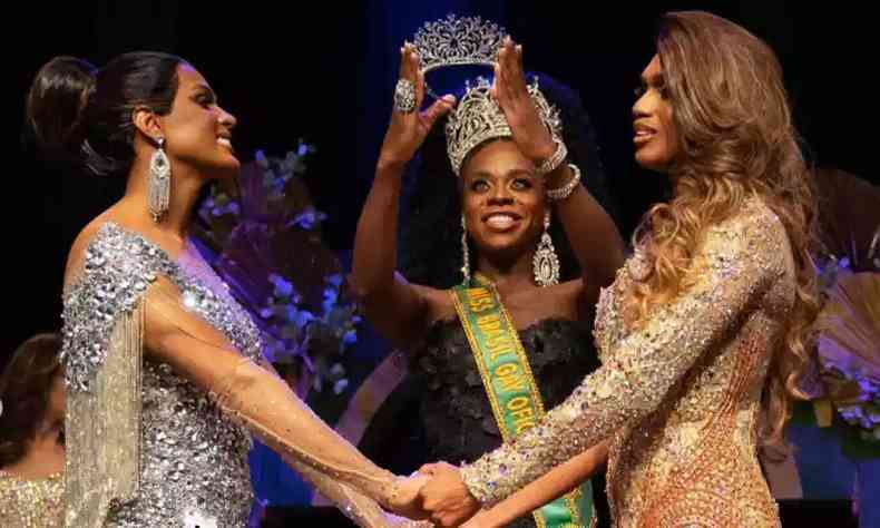 Finalistas do Miss Brasil Gay de 2022 esto de mos dadas enquanto vencedora da edio anterior ergue a coroa sobre elas