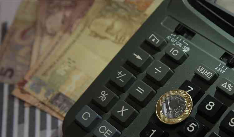 Imagem de uma calculadora com algumas cdulas e moedas