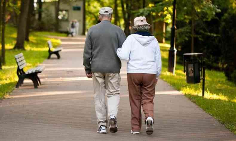 Um casal de idosos caminha em parque