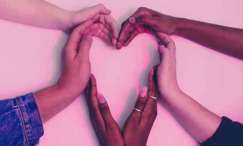 Mos de diferentes etnias formando um corao sobre um fundo rosa