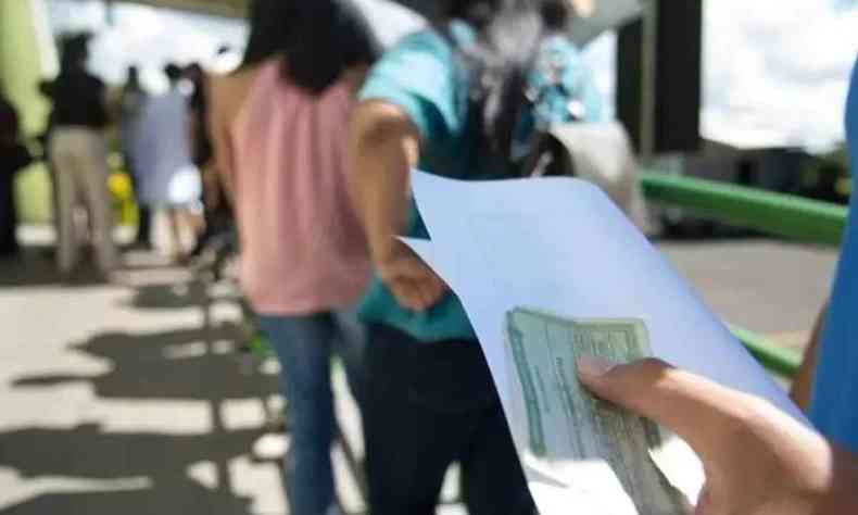 Eleitor segurando ttulo de eleitor em fila