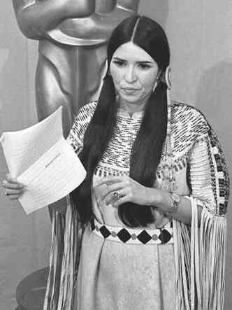 Atriz apache Sacheen Littlefeather segura papel e discursa, durante festa do Oscar em 1973