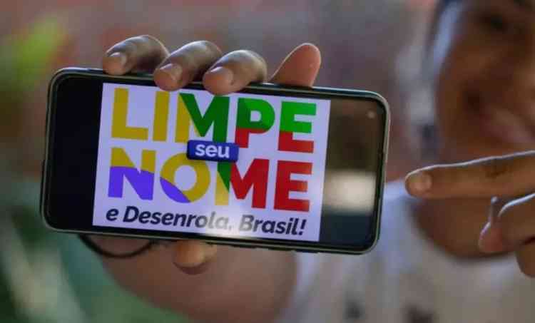 Moa mostra na tela do celular o slogan do programa do governo, Limpe o Nome e Desenrola, Brasil