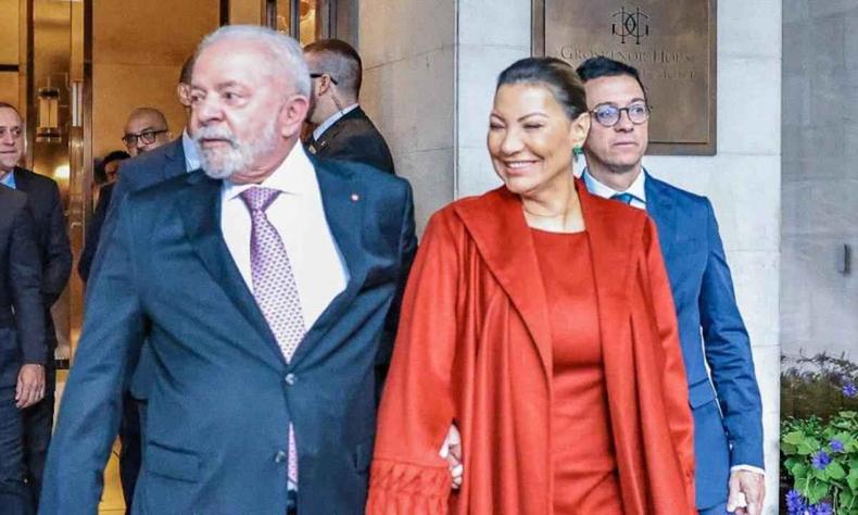 Lula e Janja andando de mos dadas. Lula, a esquerda,  um homem branco, de cabelos e barba branca. Janja, a direita,  uma mulher branca, de cabelos loiro escuro