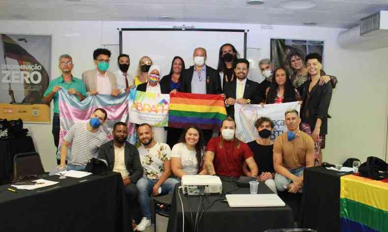 Participantes do Evento de lançamento da Campanha Educativa de Enfrentamento a LGBTIFOBIA reunidos para foto com bandeira LGBT