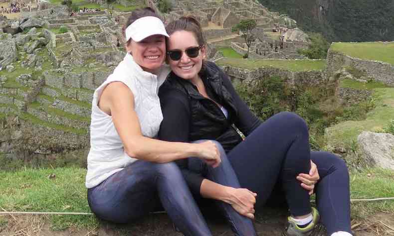 duas mulheres sentadas, me e filha, com imagem ao fundo a cidade de Machu Picchu