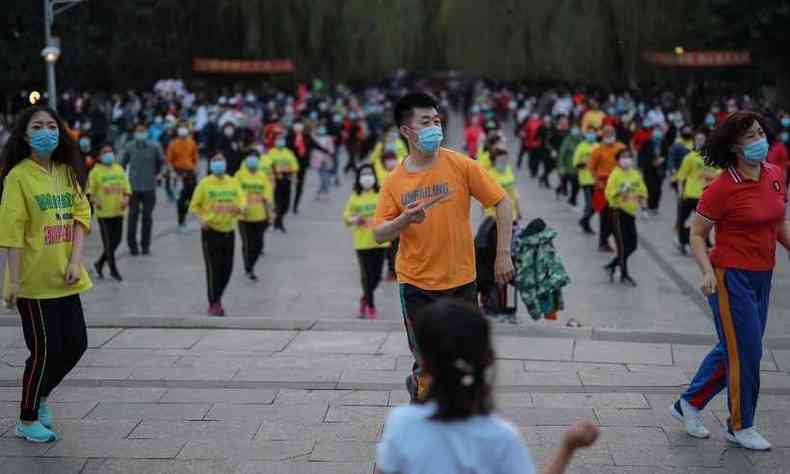Pessoas com mscaras danam em praa de Shenyang, na China(foto: STR/AFP)