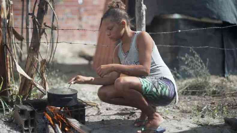 Jamile Carvalho cozinhando em um fogo improvisado