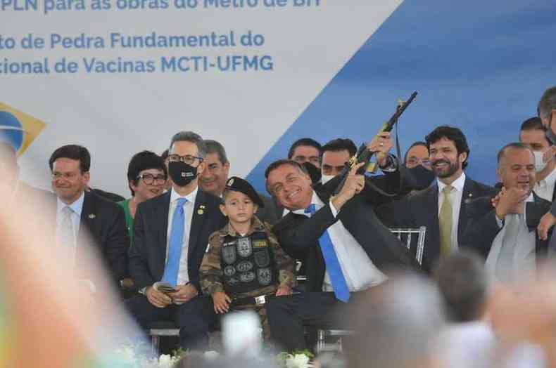 Bolsonaro segura arma ao lado de criana fardada em cerimnia na Cidade Administrativa, em BH