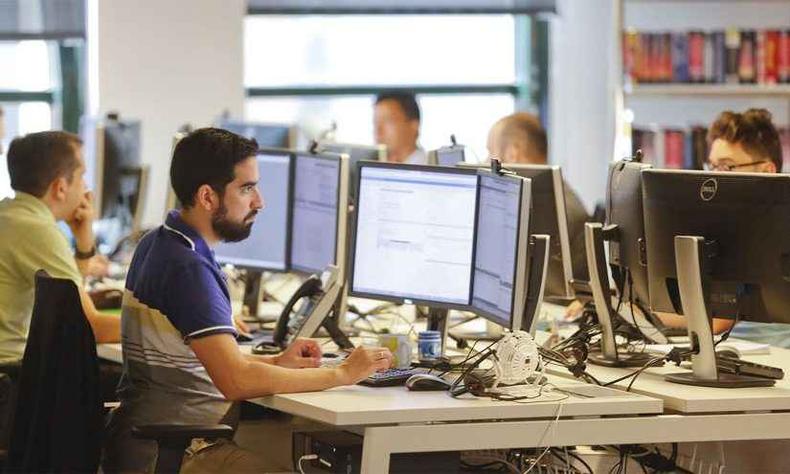 Equipe de trabalho com pessoas diversas sentadas  frente de computadores 