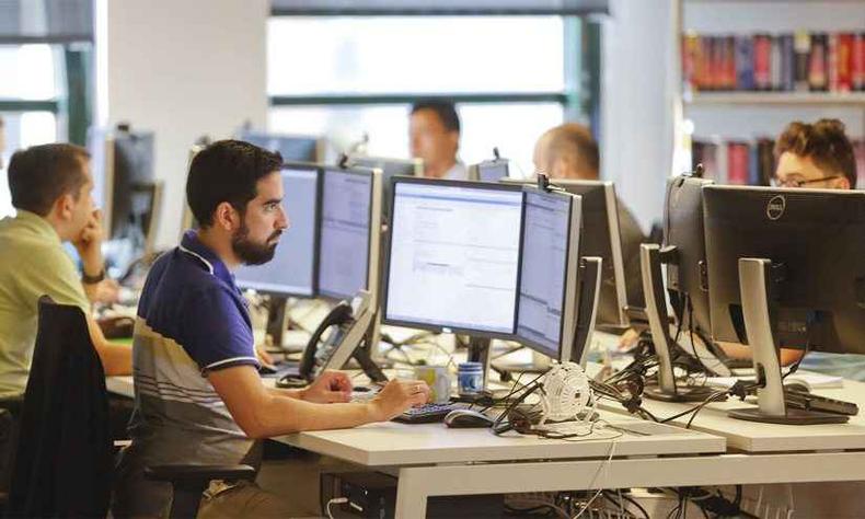 Equipe de trabalho com pessoas diversas sentadas  frente de computadores 