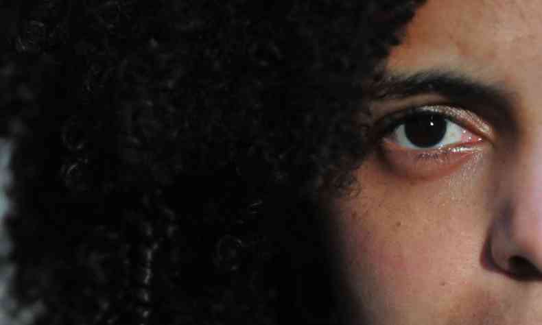 Foto de close mostra um dos olhos de jovem negra e parte dos seus cabelos crespos