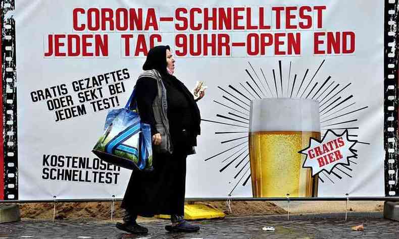Mulher passa em frente a mural que oferece cerveja de graa a quem fizer teste de COVID-19 em Dortmund, na Alemanha