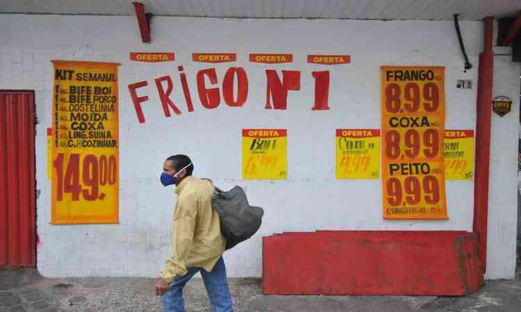 Porta de um aougue escrito 'Frigo nmero 1', com os preos ao redor e uma pessoa passando com uma mochila na frente