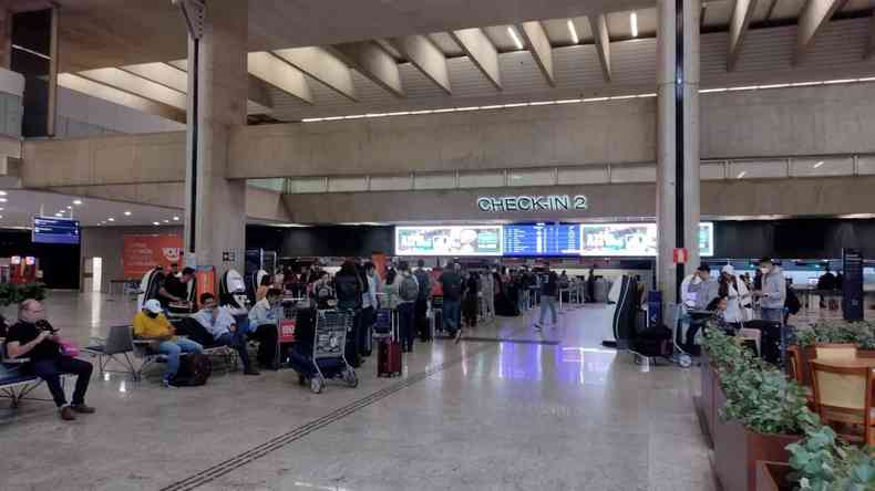 Saguão de um aeroporto com as pessoas sentadas esperando o voo