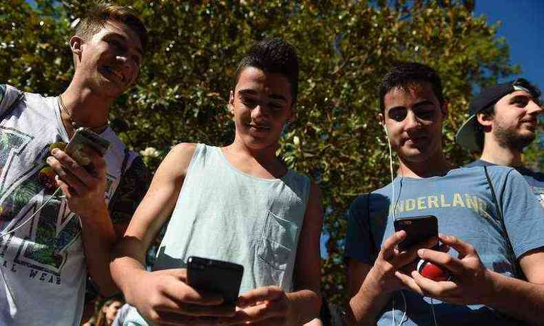 Gamers usam o aplicativo Pokemon Go em seus telefones celulares durante a caminhada em um parque de Barcelona(foto: AFP / JOSEP LAGO )