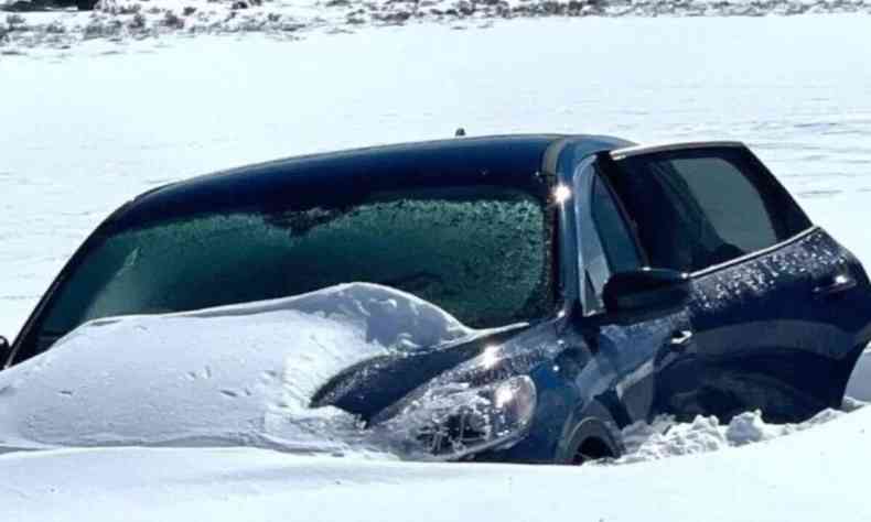 Carro visto de frente enterrado parcialmente na neve. 