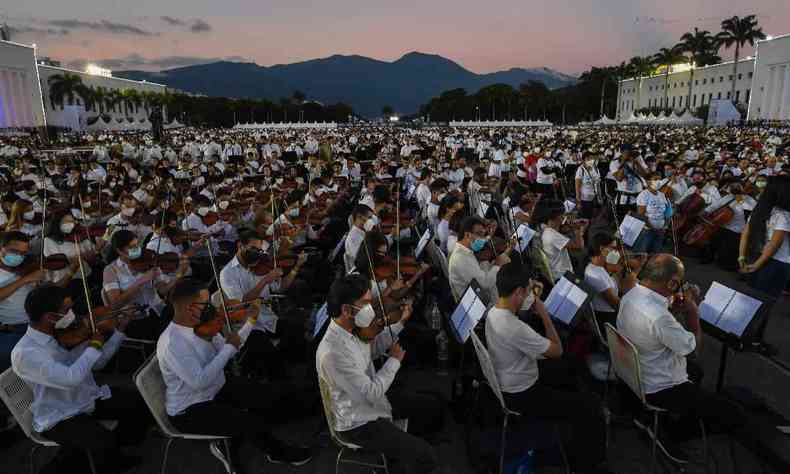 longas fileiras de msicos usando blusas brancas e calas pretas tocam em Caracas