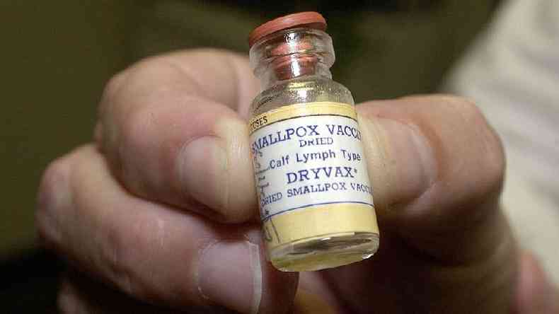 Mo segurando frasco de vacina contra varola