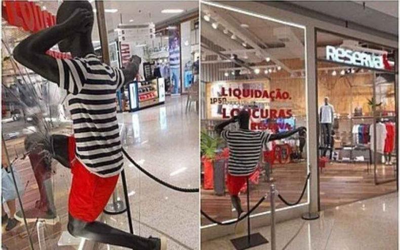 Manequim preto com a perna encaixada em uma vidraa, como se estivesse prestes a estilha-la