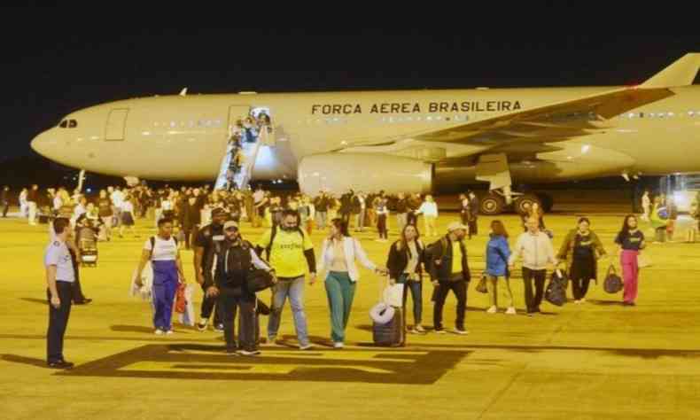 brasileiros descendo de um avio a noite