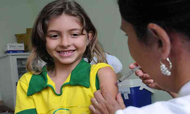 Criança sorri ao tomar a vacina da meningite, em Ouro Preto.