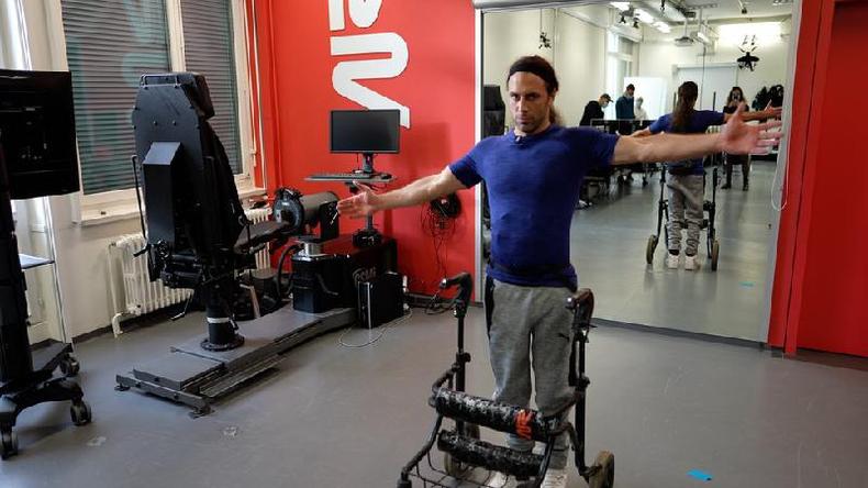Michel Roccati sofreu um acidente de moto há cinco anos e agora comemora seus novos passos(foto: BBC) Michel em pé, com braços abertos e andador na frente; ambiente é parecido com uma academia de ginástica
