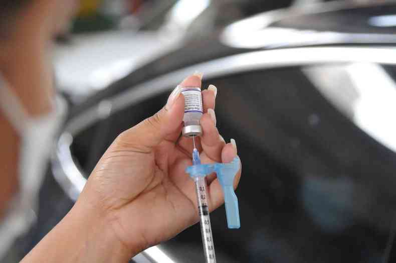 Enfermeira prepara dose de vacina na seringa 