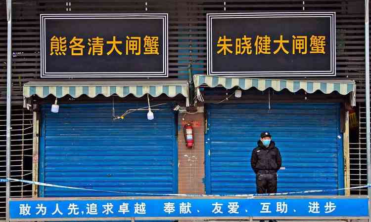 Guarda de p em frente s portas fechadas do mercado de Huanan
