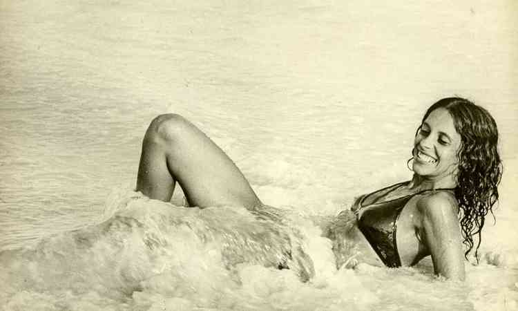 Gal Costa, jovem, sorri deitada junto s ondas