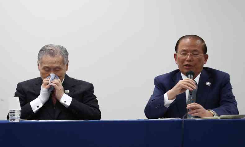 O presidente da Tquio 2020, Yoshiro Mori (E), assoa o nariz ao lado do diretor executivo, Toshiro Muto, durante anncio do adiamento(foto: Behrouz MEHRI / AFP)