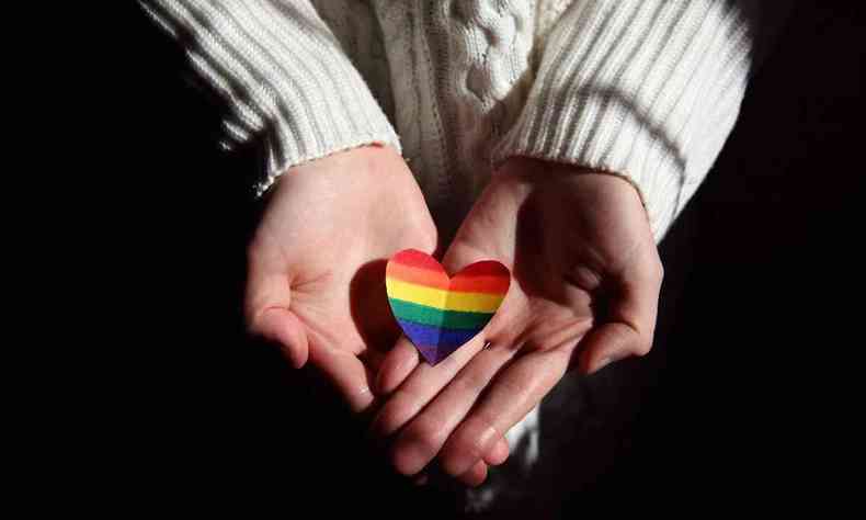 Mos segurando um corao com pintado com o arco-ris da bandeira LGBT