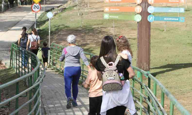pessoas caminham em uma passarela do parque ecolgico