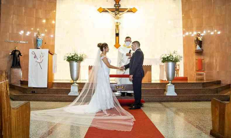 Casal no altar de mos dadas fazendo seus votos 