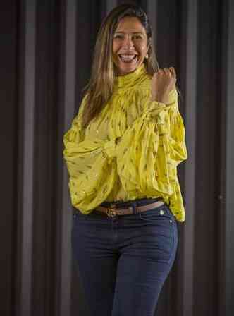 Elizabeth Aparecida de Souza Rodrigues usa camisa amarela e faz gesto de empoderamento feminino