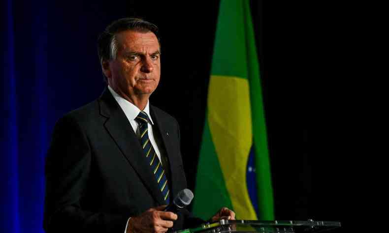 jair bolsonaro, ao fundo uma bandeira do brasil