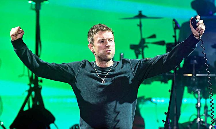 Cantor britnico Damon Albarn est no palco e olha para o lado, de braos abertos